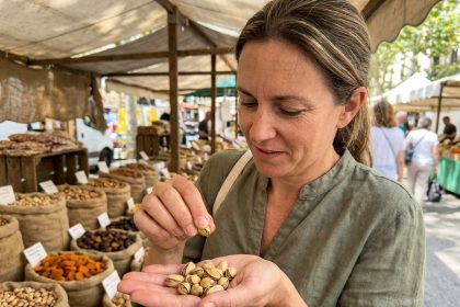 Femme examinant des pistaches de qualité sur un marché en plein air pour choisir les meilleures