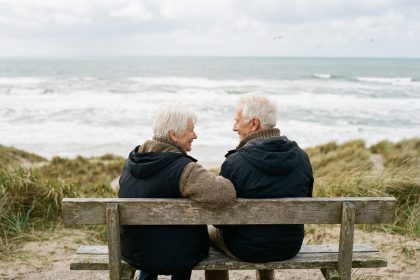 Couple agee assis sur un banc face a la mer en nature