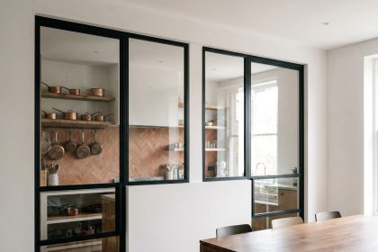 Verrière intérieure noire séparant une cuisine fermée du salon dans un appartement moderne